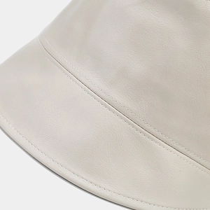 Macro view of detailed stitching and premium cream-colored faux leather bucket hat texture