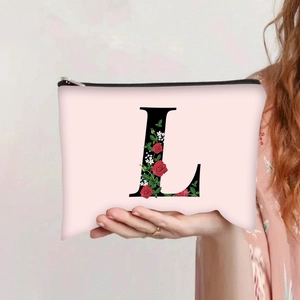Detail of pink canvas makeup bag featuring a large letter L with red floral print
