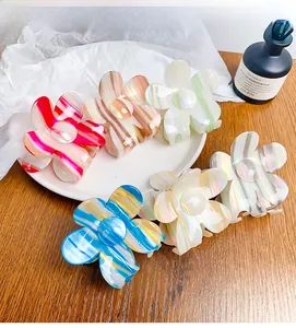 Detailed close-up of acetate flower hair claws in various colorful striped patterns