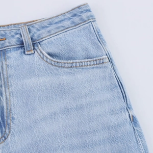 Detail of light blue denim midi skirt showing waist stitching and pocket craftsmanship