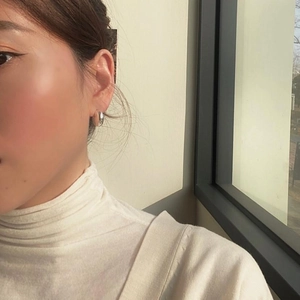 Close-up of a minimalist 925 sterling silver curved earring on a model's ear