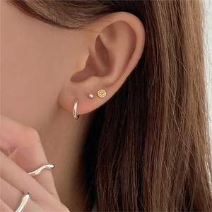 Close-up of minimalist 925 sterling silver colorful smiley face earrings and wavy rings