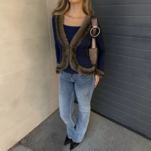 Close-up of slim fit navy top with faux fur trim on neckline and sleeve cuffs