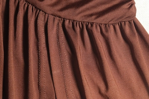 Detailed view of the brown dress side seam with pleated fabric and durable stitching