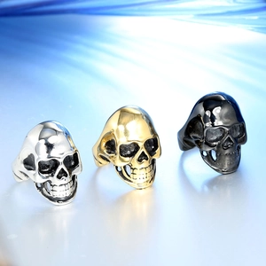 Three punk style stainless steel skull rings in gold, silver, and black metal finishes