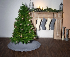 Cosy Christmas scene with grey knitted tree skirt and matching cable knit stockings on a fireplace