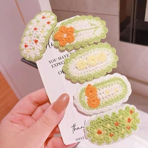 Detail view of 5-piece knitted floral hair clips with carrot and dot decorations