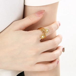 Detail of layered gold floral ring with white pearls worn on a finger