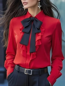 Detail of red satin blouse featuring a ruffled collar and black bow tie closure