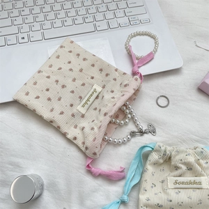 Close-up of floral corduroy cosmetic bag with pearl jewelry and luxury accessories