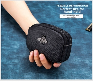 Detail of black pebbled leather coin purse with double zippers and silver bee hardware