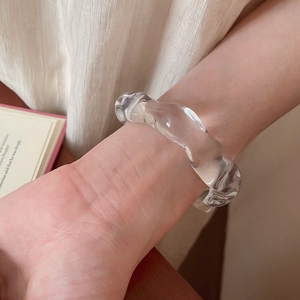 Macro detail of acrylic wave-shaped open bangle with irregular geometric transparency