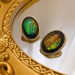 Orecchini vintage ovali in oro con smalto nero e pietre opali colorate su uno specchio