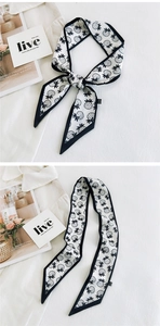 Detail showing white narrow scarf with black pineapple print and 100% polyester tag