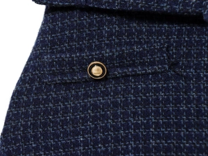 Gros plan sur la texture en tweed bleu marine et le bouton doré décoratif de la robe