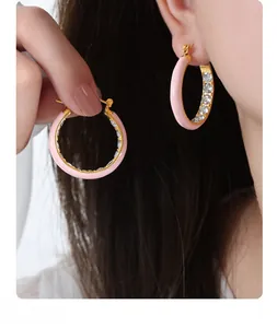 Macro shot of 18K gold earrings featuring pink enamel coating and sparkling zircon stones