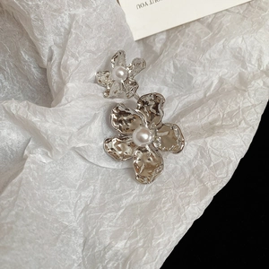 Detailed close-up of irregular silver flower earrings with pearls and hammered texture