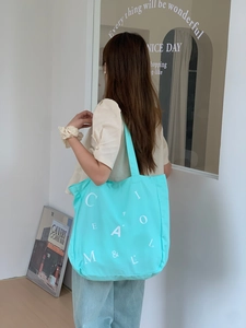 Detail der hellblauen Canvas-Tasche mit Buchstabenprints in einer Lifestyle-Innenumgebung