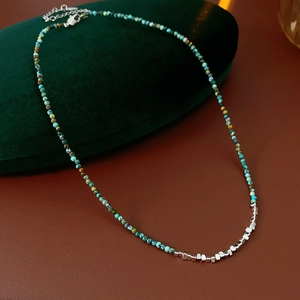 Close-up of turquoise beads and silver cubes on a beaded necklace over leather