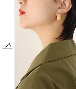 Detailed view of gold stainless steel C-shaped earrings with textured mesh pattern on a model
