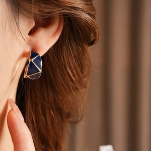 Close-up of vintage blue enamel C-shaped earrings with gold geometric lines on model