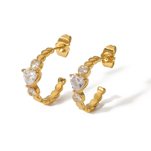 Boucles d'oreilles dorées en C avec zircons en forme de cœur sur fond blanc
