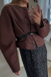 Detail view of brown long-sleeved vest with H-buckle belt and sequined black skirt