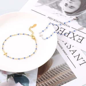 Detailed view of blue beaded cross bracelets set in gold and silver finish on white plate