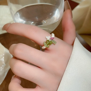 Detail of handmade beaded flower ring with pink glass petals and green accent stones