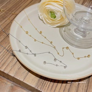 Detailed view of minimalist gold and silver beaded necklaces on a white decorative plate