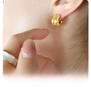 Detailed view of C-shaped 18K gold plated surgical titanium steel hoop earrings on model