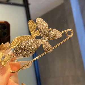 Detailed macro view of a gold butterfly brooch pin with sparkling white rhinestones