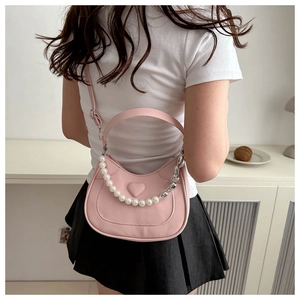 Detail of pink saddle bag featuring a 3D heart motif and pearl metal chain strap