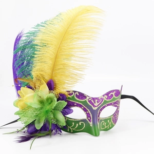 Macro detail of masquerade mask featuring colorful feathers and gold glitter accents