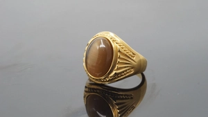 Detail of a gold vintage ring featuring an oval brown cat's eye stone and carved stripes
