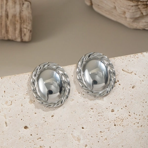 Macro shot of silver oval stud earrings with twisted rope border on natural stone