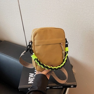Detail of earth-tone canvas crossbody bag with thick woven handle on luxury book