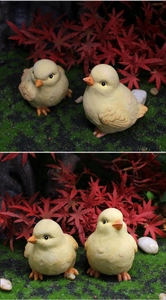 Macro detail of miniature resin chicken figurines with realistic feather texture in a garden