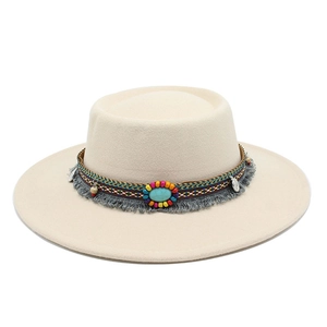 Détail d'un chapeau fedora en laine avec perles turquoise et décoration de pompons à franges