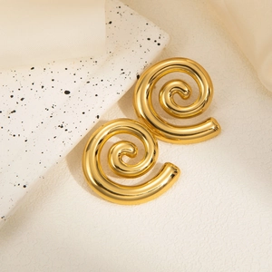 Macro detail of gold spiral hoop earrings with polished finish on cream silk fabric