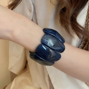 Detail of dark blue marble-textured acrylic resin bracelet links on a woman's wrist