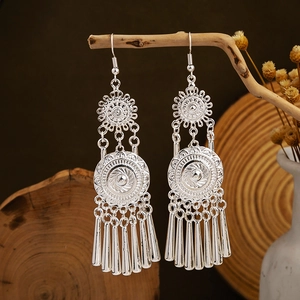 Detail of silver ethnic leaf tassel earrings hanging on branch in rustic bohemian style