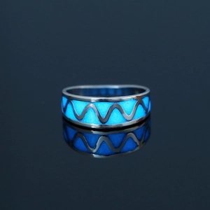 Close-up of luminous heart ring glowing blue in dark with reflective surface