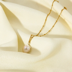 Macro detail of natural Baroque pearl pendant on golden beaded stainless steel chain