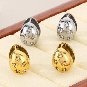 Detail of egg-shaped gold and silver earrings with star engraving in a velvet box
