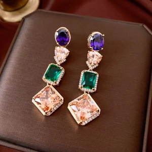 Macro detail of luxury gold earrings featuring multi-color gemstones and pavé crystals