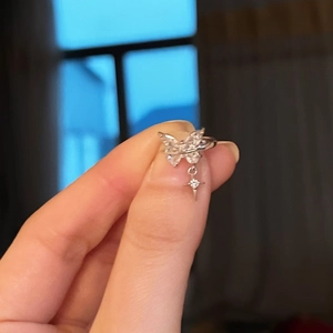 Detailed macro view of zircon butterfly ear clip with a hanging star charm design