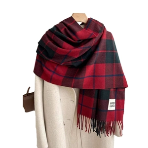 Thick red and green plaid cashmere-feel scarf with tassels on a beige wool coat