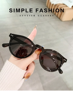 Detail of hand-held black round frame polarized sunglasses with stylish rice nail accents