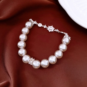 Detailed macro view of cream white pearls with silver snowflake clasp on dark velvet fabric